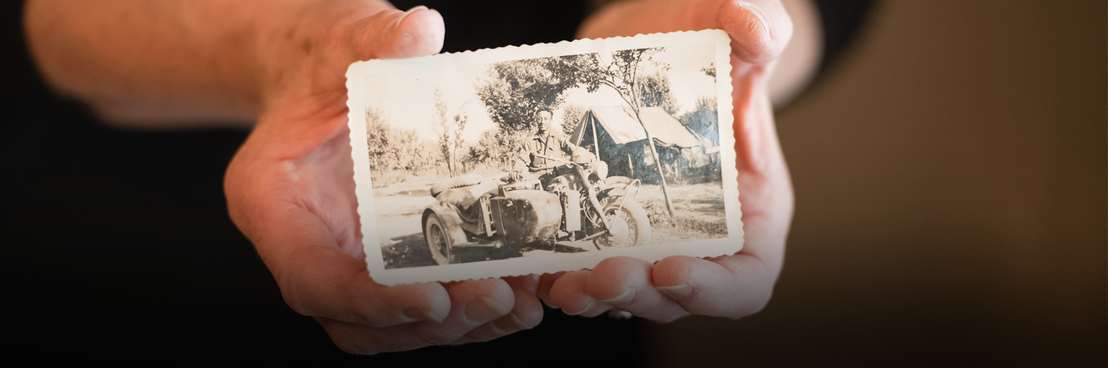 Nelwyn Landreth's hands are seen holding a photo of her father, Roy Thomas "Smiley" Pruitt. In the picture he's sitting on a motorcycle.