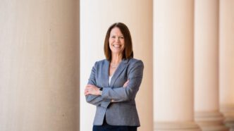 Denise Anderson stands with her arms crossed, the columns of Sikes Hall shown behind her.