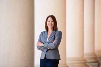 Denise Anderson stands with her arms crossed, the columns of Sikes Hall shown behind her.