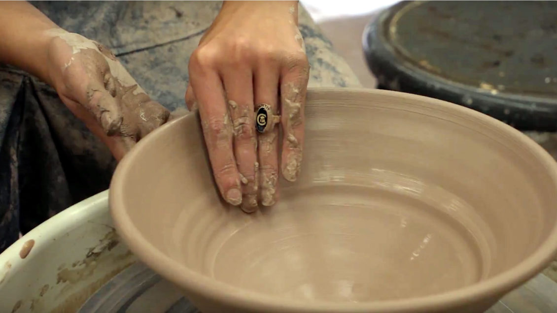 A student shapes a bowl in the studio.