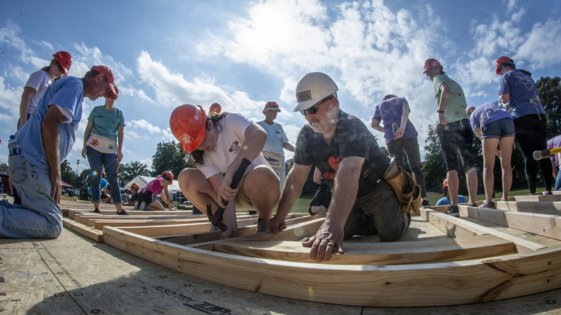 Pastor Chris Heavner holds boards together while a student hammers the board while working on the Habitat for Humanity home build on Bowman Field.
