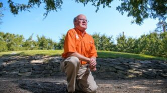 Dave Lyle kneels by the Scroll of Honor.