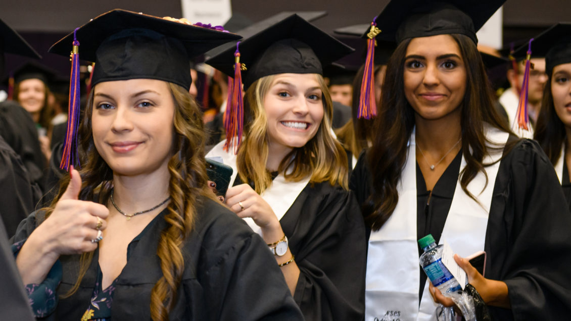A graduate gives a thumb's up before getting her diploma.