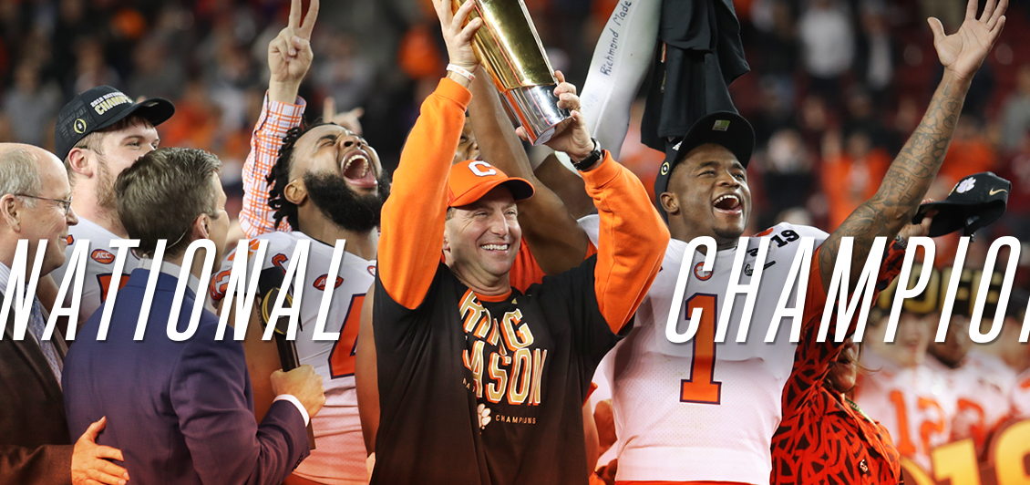Coach Dabo Swinney and the football team hold up the National Championship trophy whil confetti falls around them.