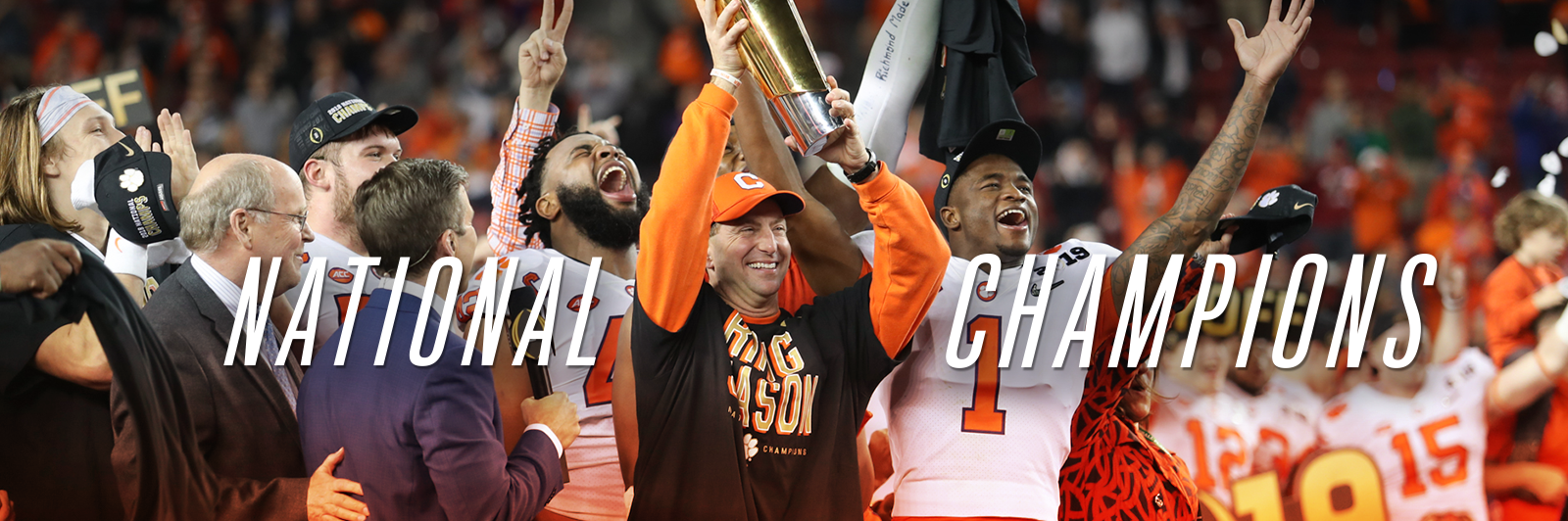 Coach Dabo Swinney and the football team hold up the National Championship trophy whil confetti falls around them.