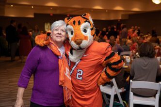 Emily Wallace smiles and poses with the Tiger mascot.