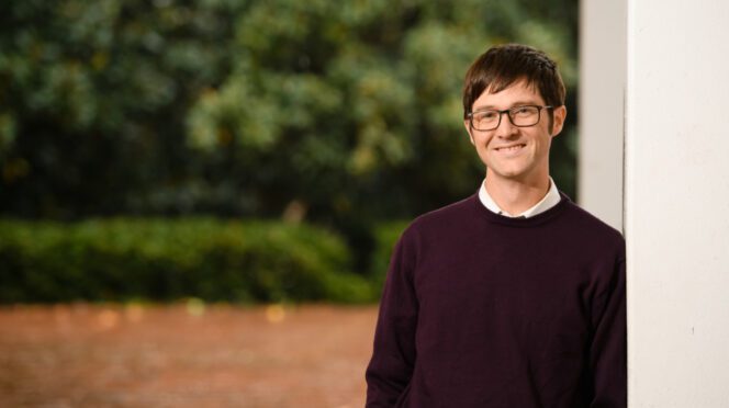 Patrick Warren leans against a column, posing for a photo.