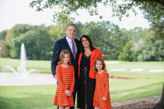 Ben, Cheri, Ali, and Dani Phyfer smile together outside the Madren Center overlooking the Walker Course.