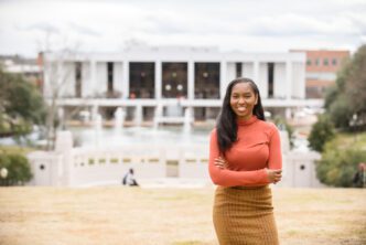 Sarah Dumas stands with her arms crossed with the Clemson R.M. Cooper Library in the background.