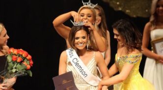 Wearing a white dress, the newly announced Miss Clemson is excited as a former winner is crowning her.
