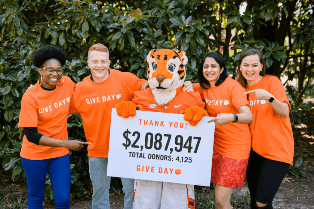 Clemson students and faculty stand with the cub holding a sign with total amount raised.