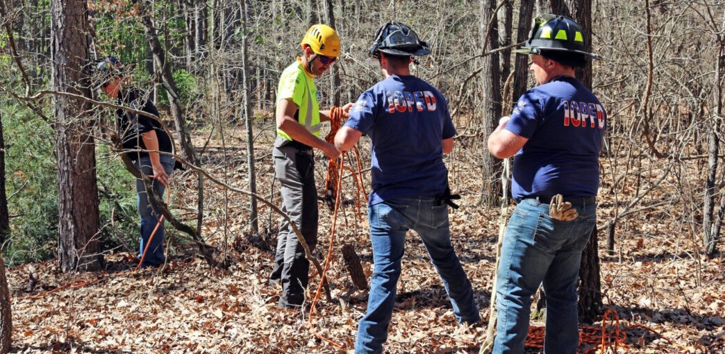 Instructor demonstrates chainsaw safety techniques to firefighters.
