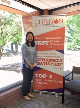 New employee standing at Clemson banner.