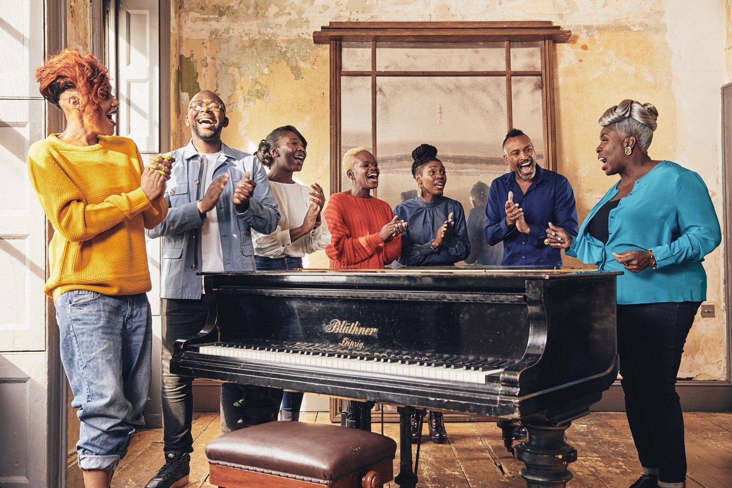 Members of the Kingdom Choir stand in a semi-circle around a piano and sing.