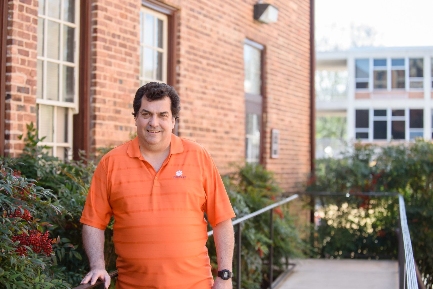 Michael Childress leans against a handrail outside a brick building on Clemson's campus.