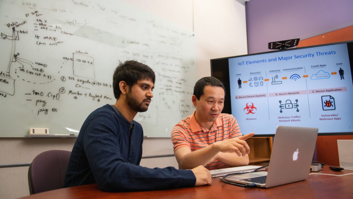 Hongxin Hu, right, works with a student in Clemson University's McAdams Hall.