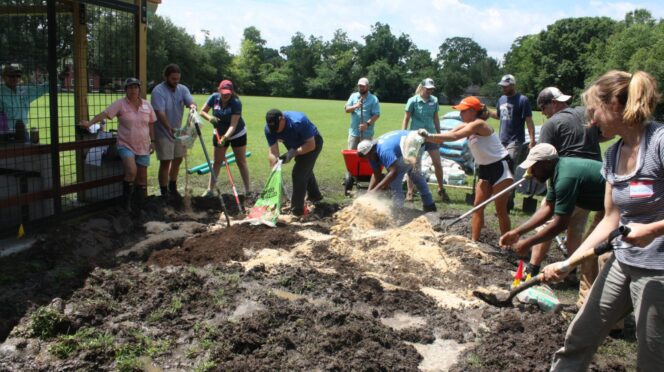 People adding soil ammendment to garden bed