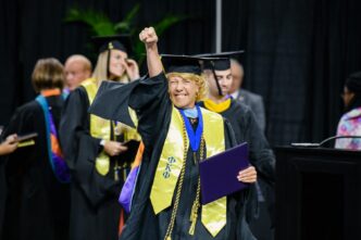 Paige Zoltewicz smiling big while awaiting to shake President Jim Clements' hand at August 2019 graduation.