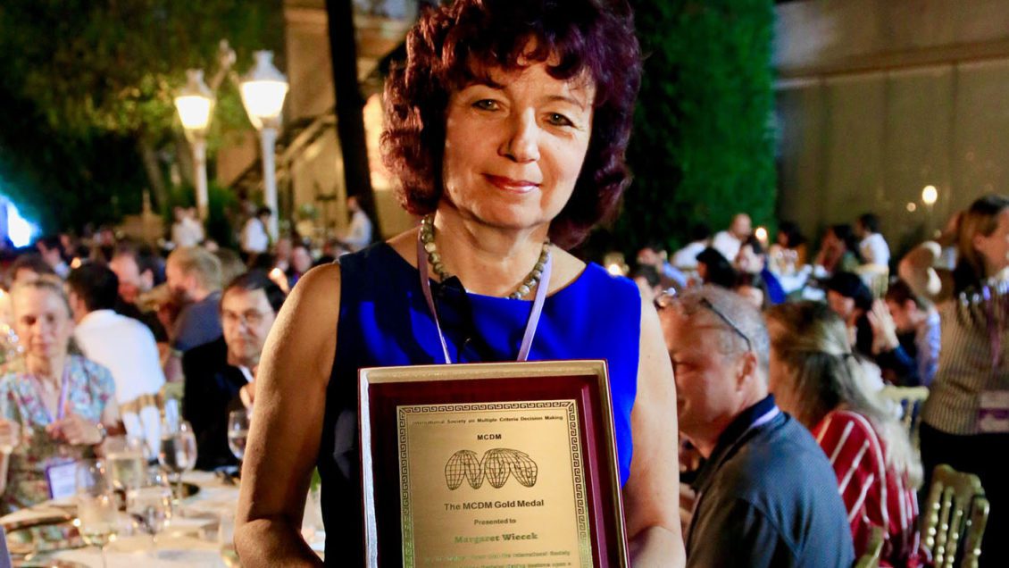 Professor Margaret Wiecek holding Gold Medal award.