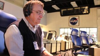 Man sits in NASA control center working on computer.