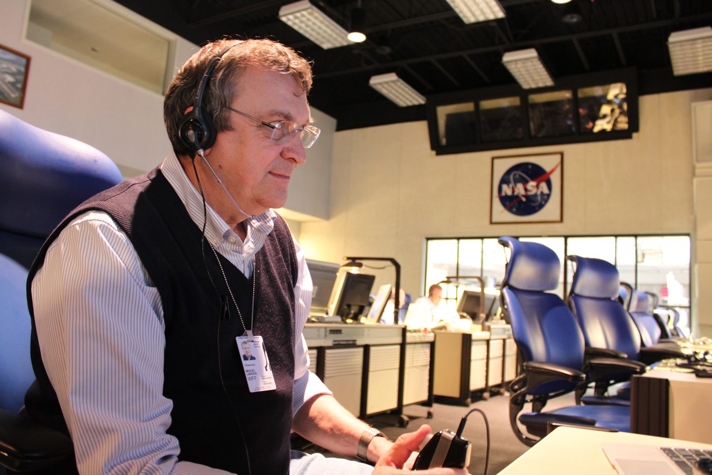 Man sits in NASA control center working on computer.