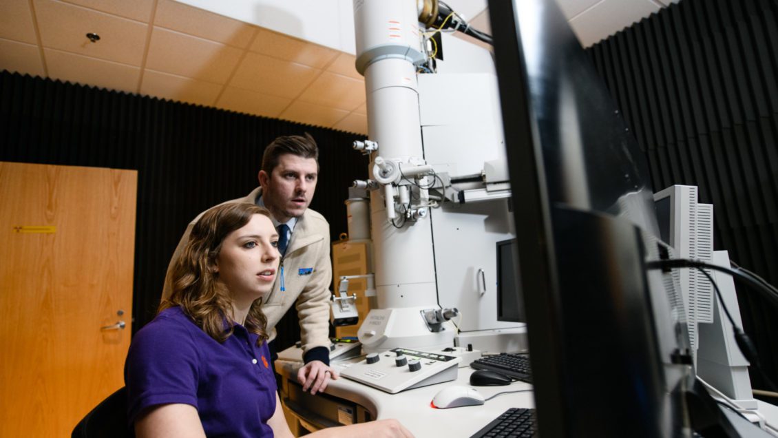 Clemson University Ph.D. student Allison Domhoff and Eric Davis, assistant professor of chemical and biomolecular engineering, use an electron microscope to analyze nanometer-sized particles.