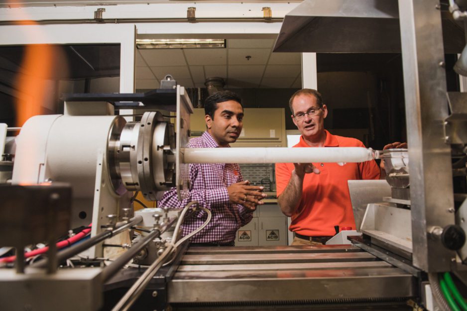 Kapil Chalil Madathil (left) and John Ballato talk about a lathe used to make optical fiber.