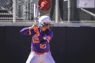 A softball player stands at bat waiting for the pitch.
