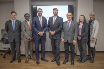 A group of seven people stand in front of a large digital screen