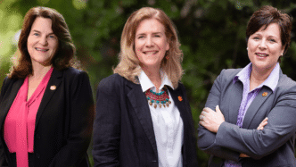 3 women in suits stand to have their photos taken