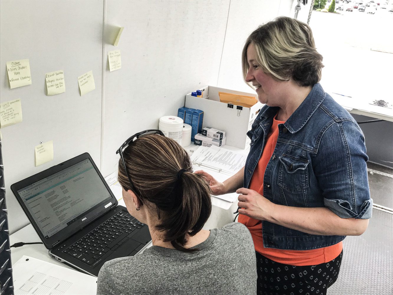 Alanna Landreth (standing) shows Vicki Roberts how to log an incoming work request for Oconee County Emergency Services. The two are among 40+ employee volunteers from Clemson University aiding Seneca tornado victims.