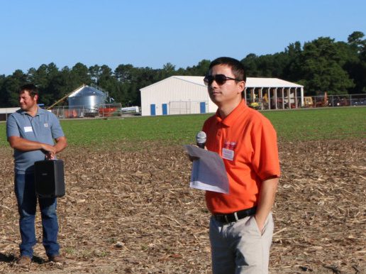 Rongzhong Ye standing in a farm field presenting to farmers.
