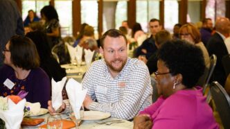 A man and a woman sit talking at a table.