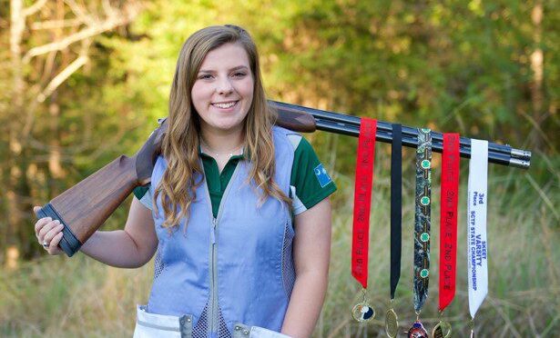 Tatelyn Benton poses with her shooting medals and shotgun.