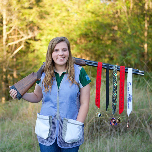Tatelyn Benton poses with her shooting medals and shotgun.