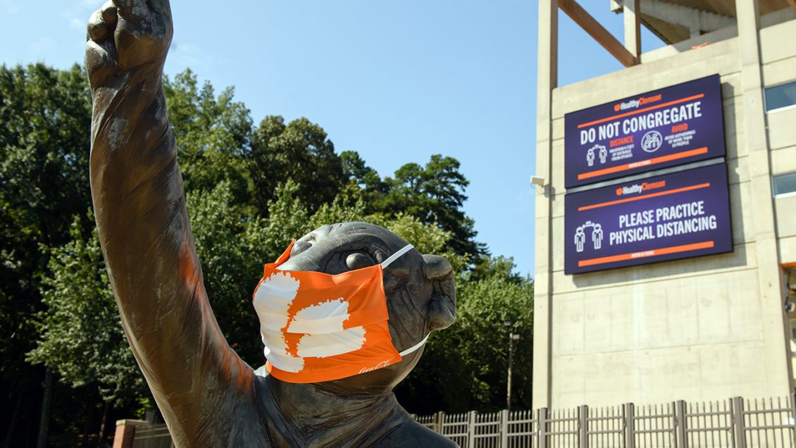 The Tiger Cub statue outside the stadium wears a mask in front of Healthy Campus signs promoting healthy behavior.