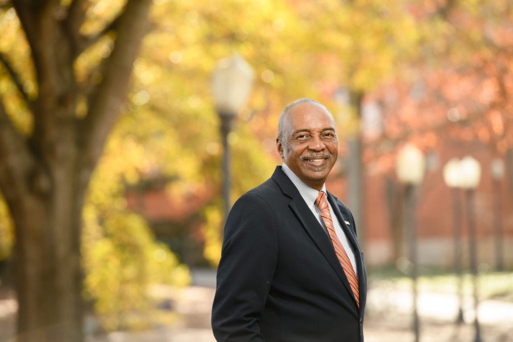 Man in suit in front of fall trees