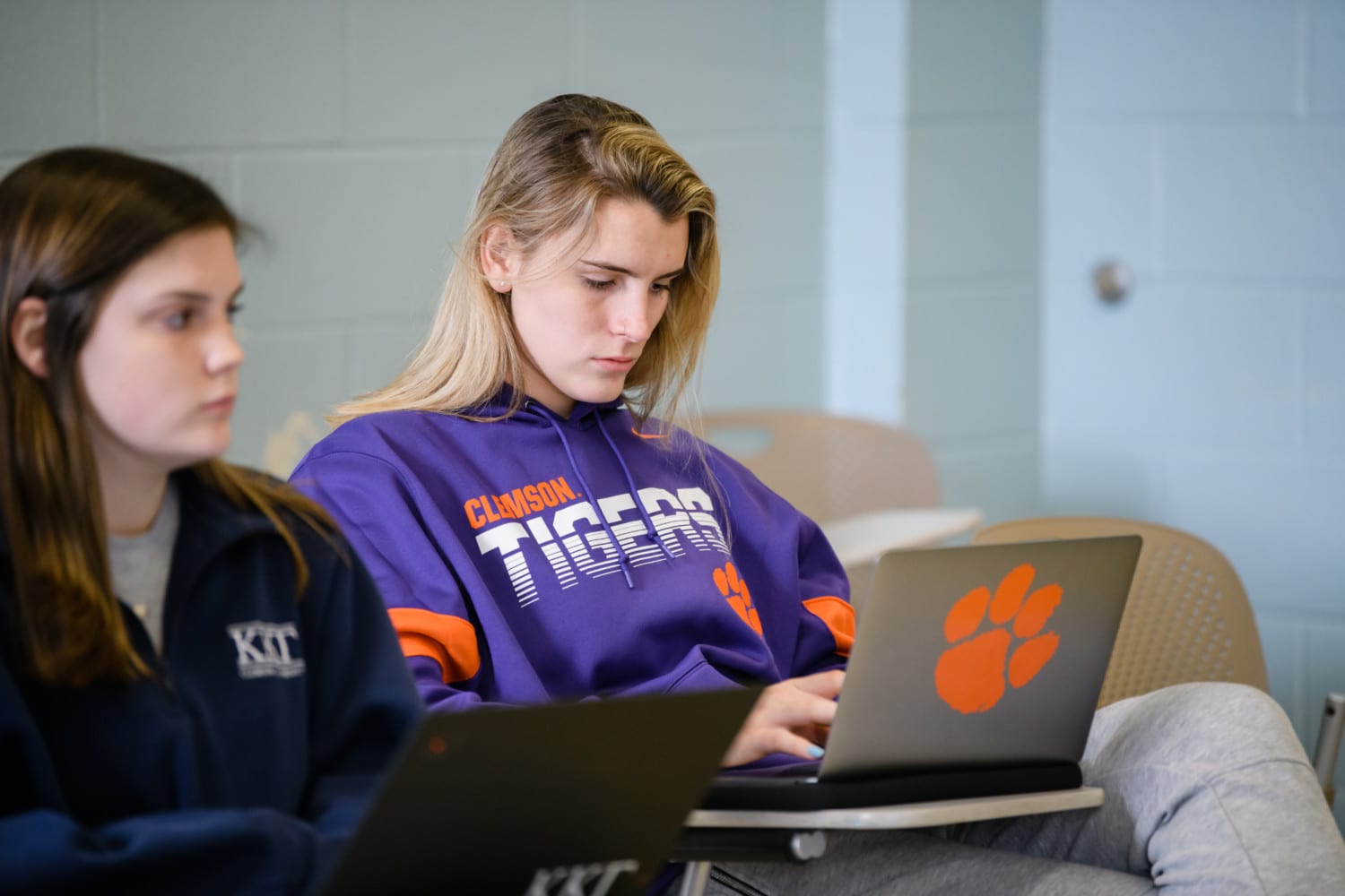 A Clemson student types on a laptop inside a classroom