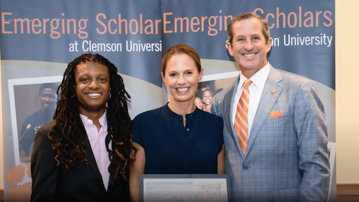 Mark and Kathryn Richardson pose with a student in front of an Emerging Scholars banner