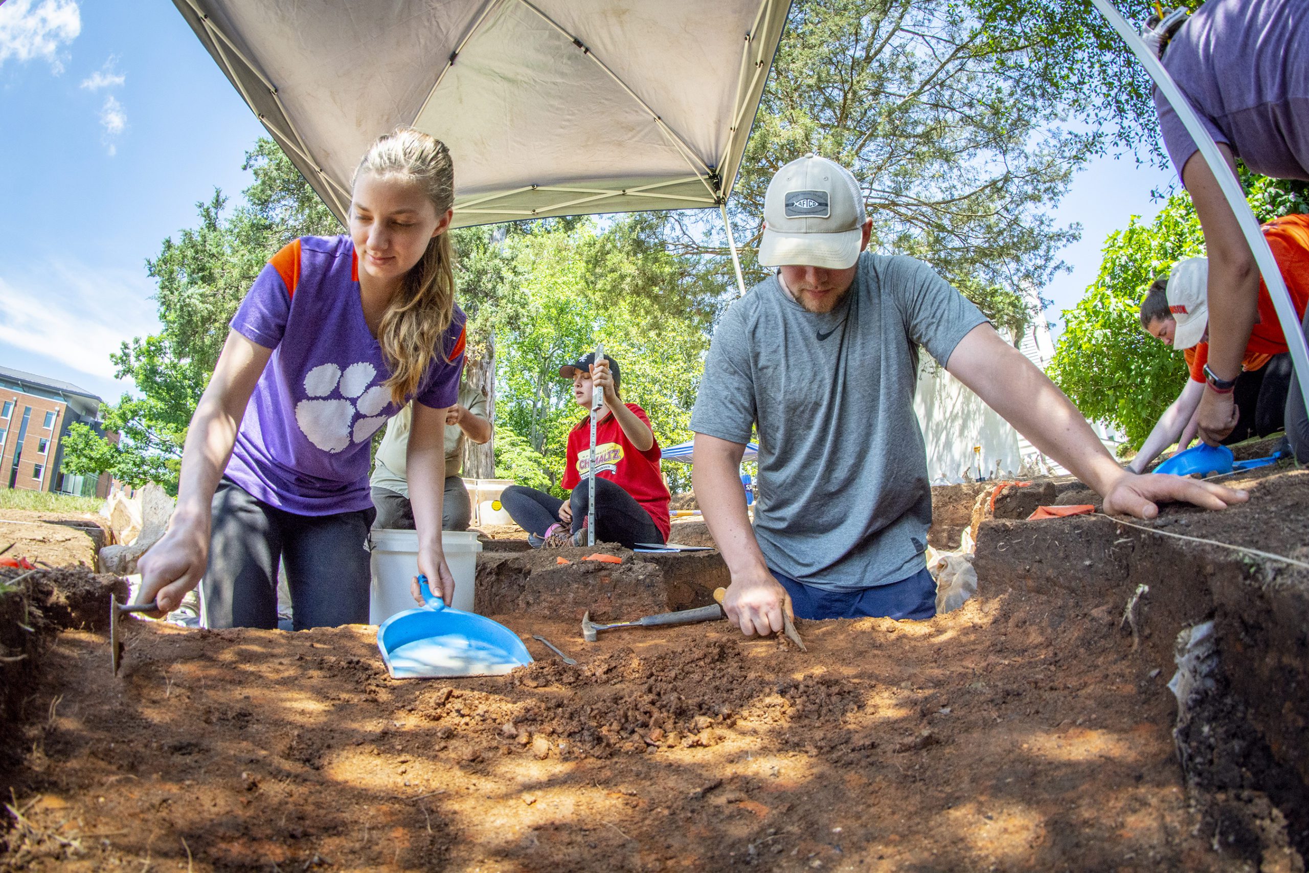Male and female student digging at an archeological site.