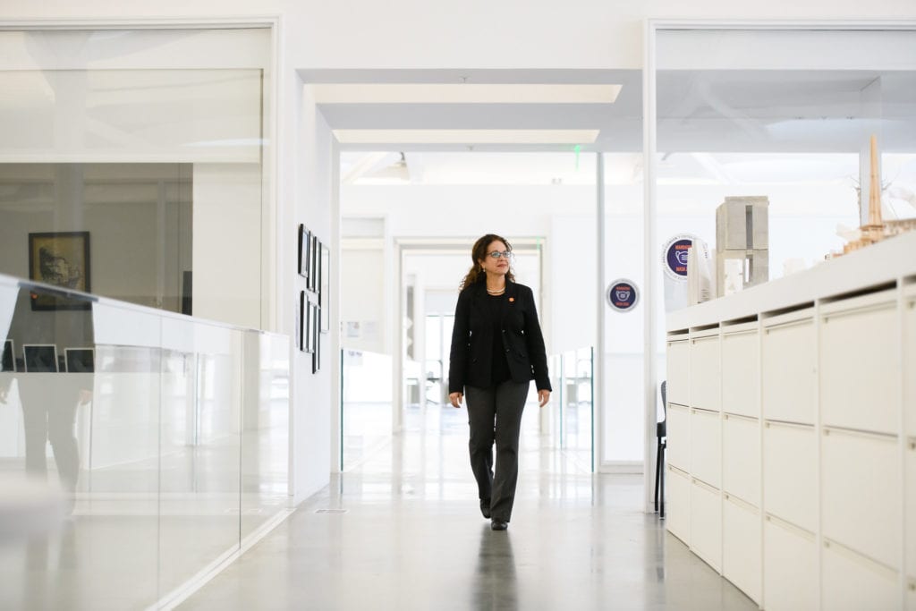 Woman in black suit walking down white hallway