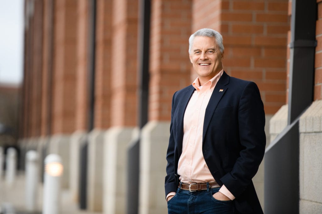 Man in black suit with orange shirt outside