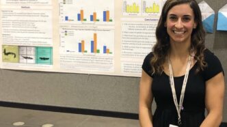 Stephanie LaPlaca standing in front of a display of her tire wear particle research