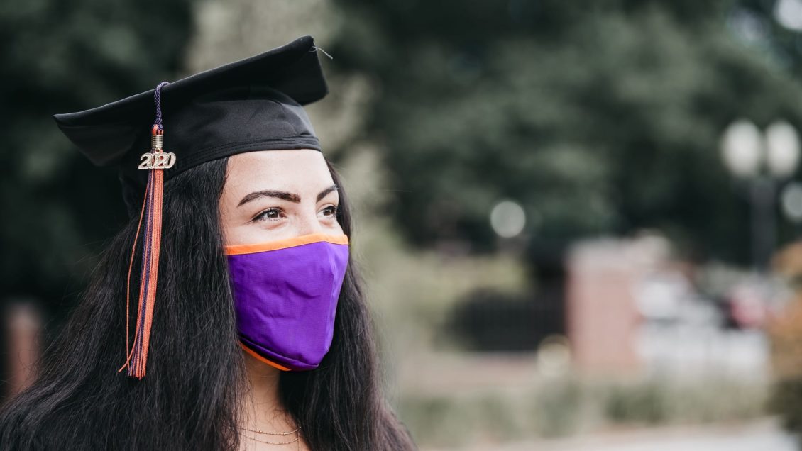 Female student in graduation hat and facemark