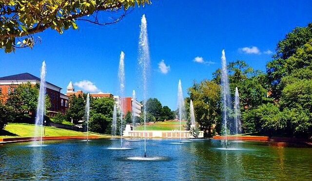 A wide campus view of the library with fountains in the reflection pool spraying in the foreground.