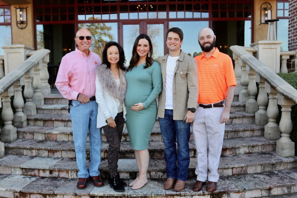 An outdoor portrait of the Glenn family standing on steps outside a home. 