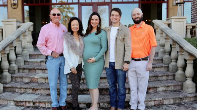 An outdoor portrait of the Glenn family standing on steps outside a home.