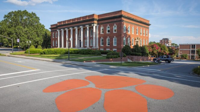 An orange Clemson tiger paw painted on the street in front of Sikes Hall.