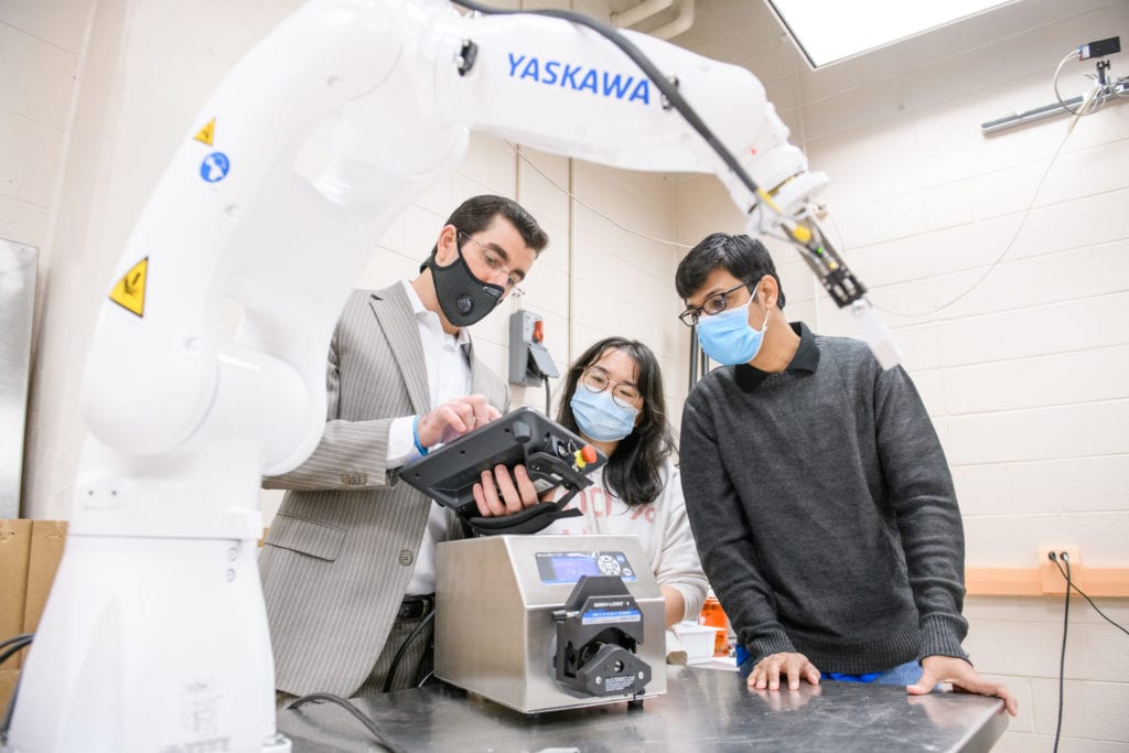 (Left to right) Brandon Delspina, Sophie Wang and Yu Zhanh inspect their open-source benchtop robot that can fill, cap and seal sterile syringes.