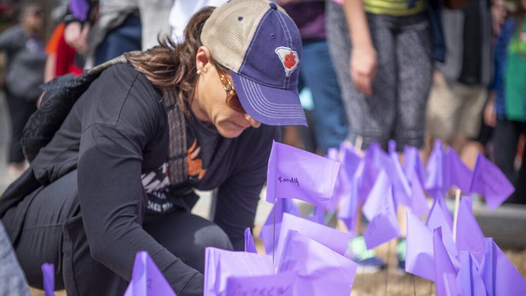 One of more than 300 people who took part in the 2019 Out of the Darkness Walk at Clemson University places a flag in the North Green area
